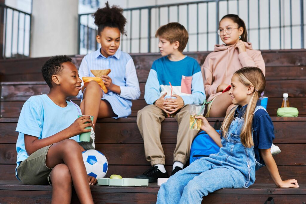 Youthful intercultural school friends with soda looking at one another Youthful intercultural school friends with soda looking at one another