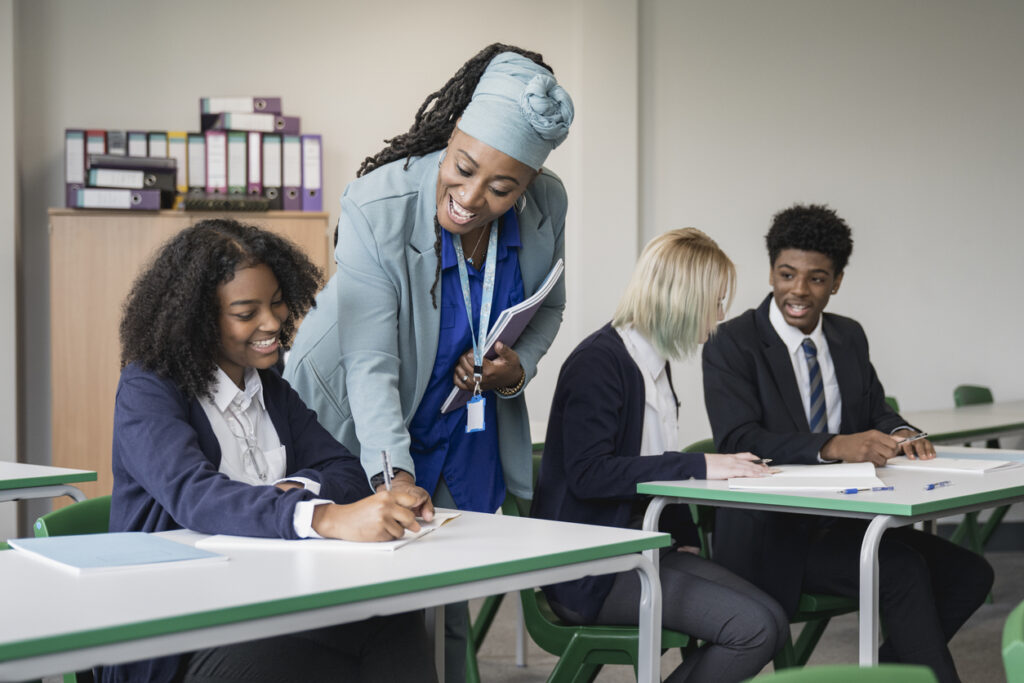 Cheerful teacher helping student in secondary classroom Cheerful teacher helping student in secondary classroom