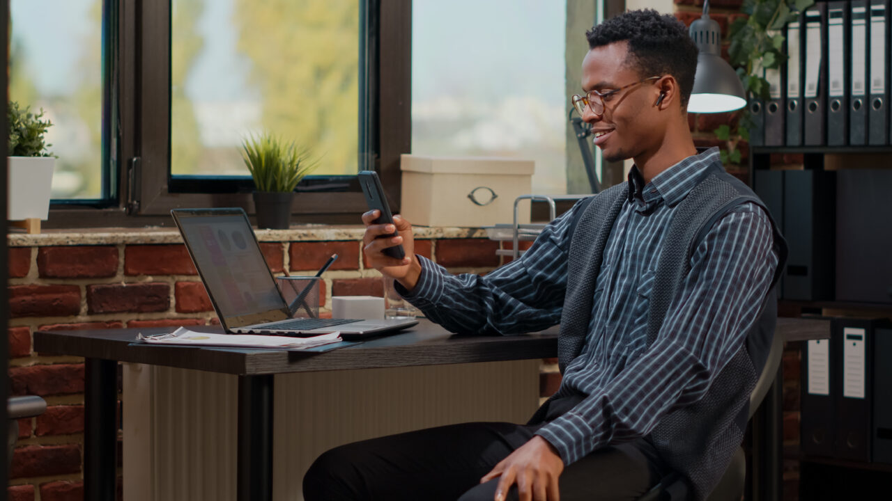 Office worker using smartphone to talk on video call at job Office worker using smartphone to talk on video call at job